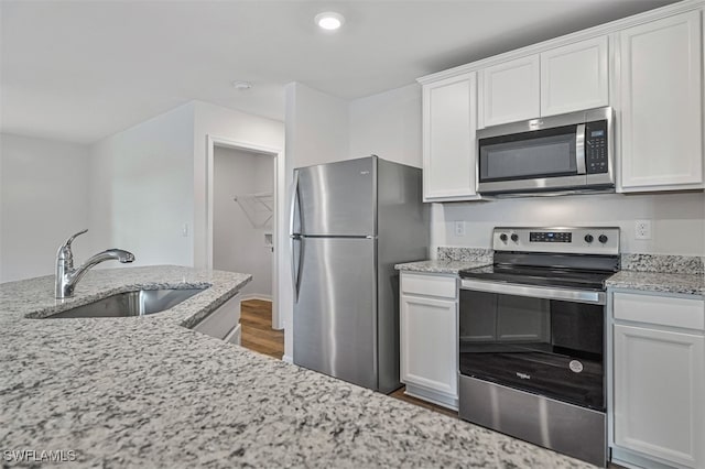 kitchen featuring light stone counters, sink, white cabinets, and stainless steel appliances