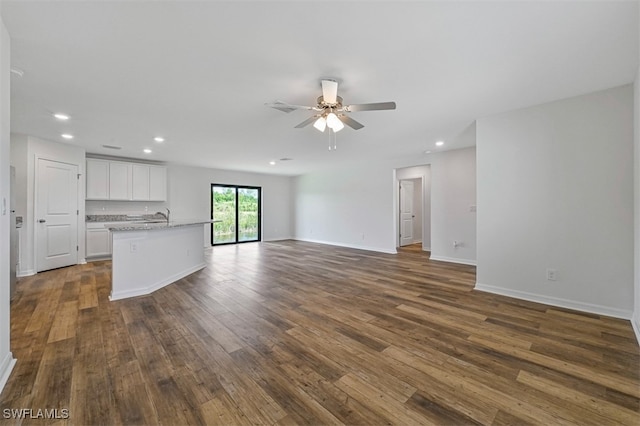 unfurnished living room featuring ceiling fan, dark wood-type flooring, and sink