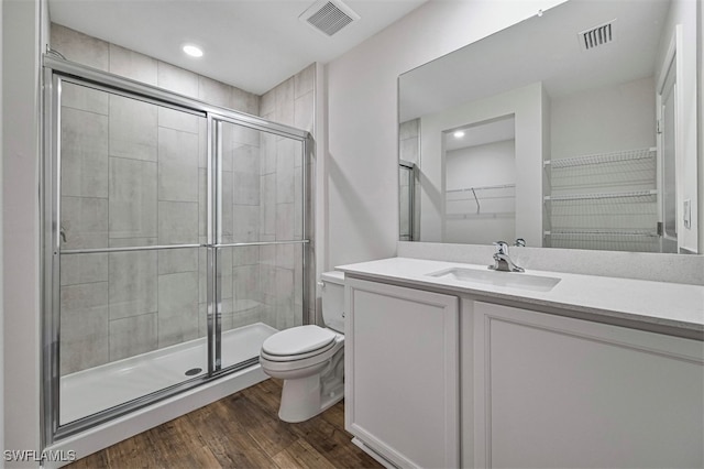 bathroom with toilet, vanity, wood-type flooring, and walk in shower