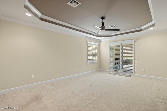 unfurnished room featuring ceiling fan, a raised ceiling, crown molding, and light carpet