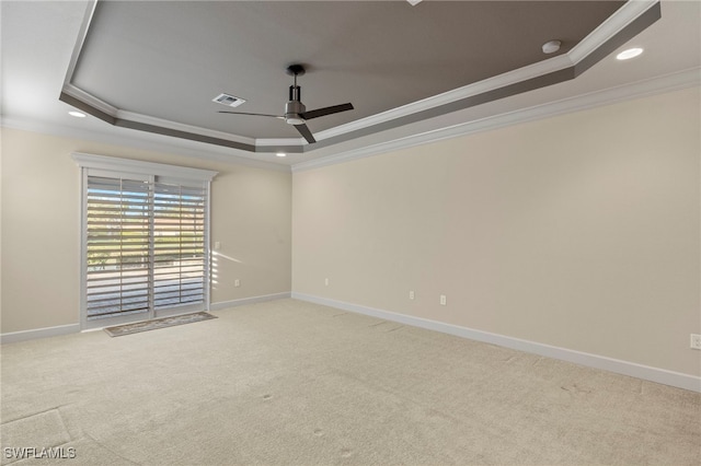 carpeted empty room with a raised ceiling, ceiling fan, and crown molding