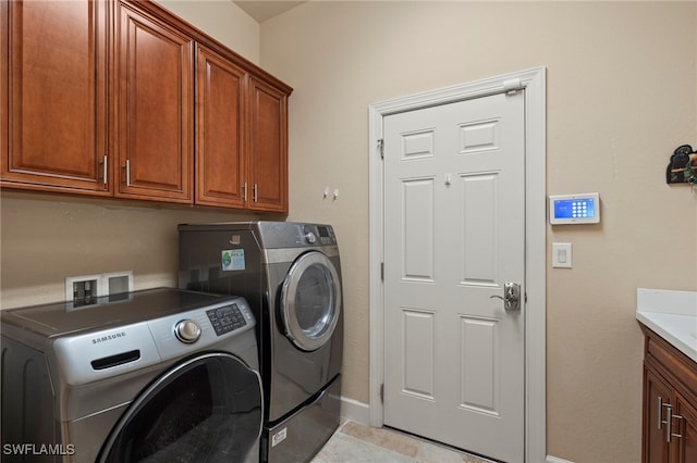 clothes washing area with cabinets, light tile patterned flooring, and washing machine and clothes dryer