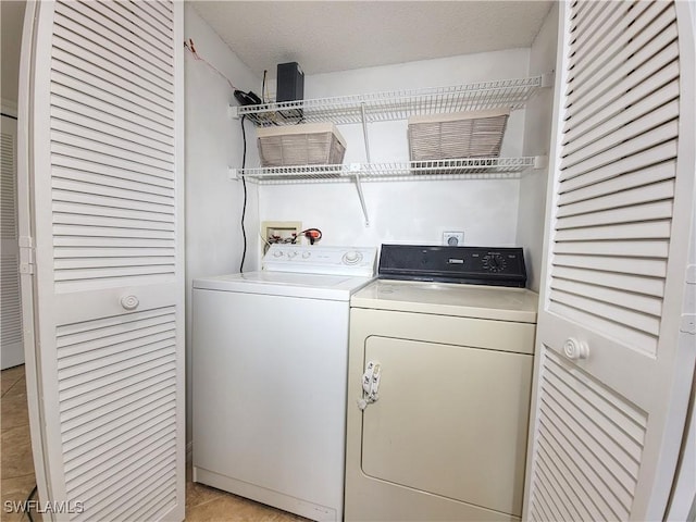 laundry area with light tile patterned floors, washer and dryer, and a textured ceiling