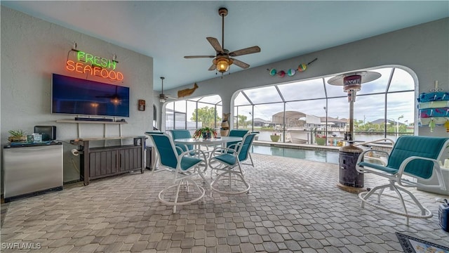 exterior space with a lanai, ceiling fan, and a water view