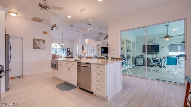 kitchen with lofted ceiling, sink, light stone countertops, stainless steel appliances, and white cabinets