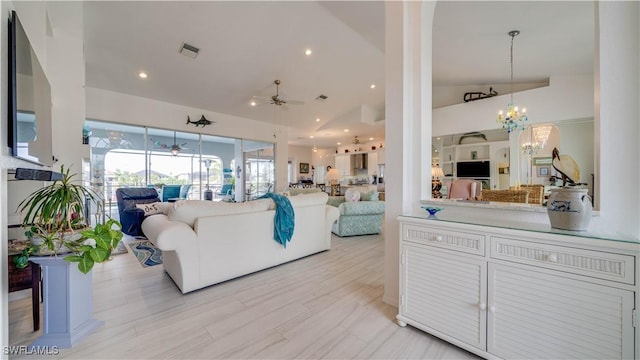 living room with high vaulted ceiling and ceiling fan with notable chandelier