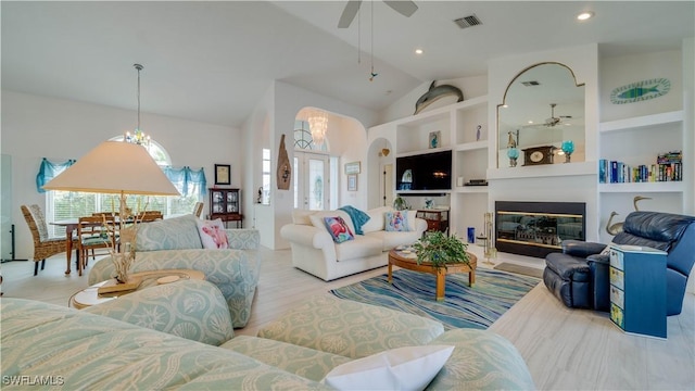 living room featuring ceiling fan, lofted ceiling, light hardwood / wood-style floors, and built in shelves