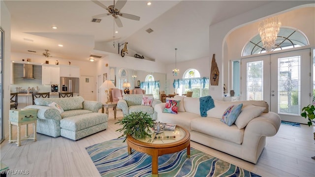 living room featuring high vaulted ceiling, a healthy amount of sunlight, french doors, and ceiling fan with notable chandelier