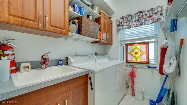 clothes washing area with washing machine and dryer, sink, and cabinets