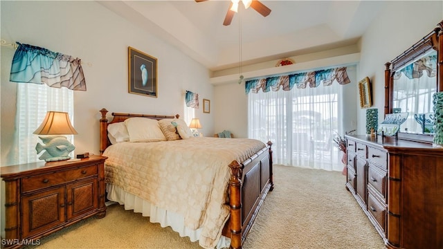 carpeted bedroom with ceiling fan, access to exterior, and a raised ceiling