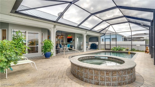 exterior space featuring glass enclosure, a patio, and an in ground hot tub