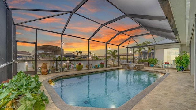 pool at dusk featuring glass enclosure and a patio area