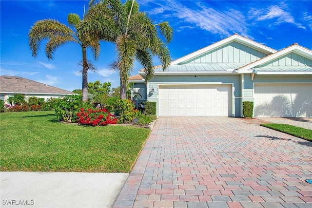 single story home featuring board and batten siding, decorative driveway, an attached garage, and a front lawn