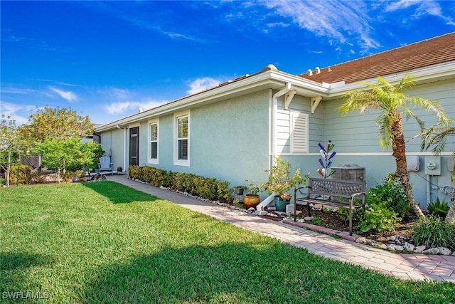 view of side of home with a lawn and stucco siding