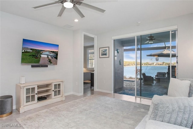 living room with recessed lighting, a water view, a ceiling fan, baseboards, and tile patterned floors