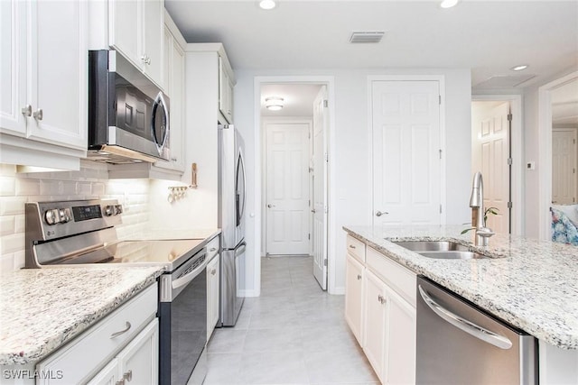 kitchen with a sink, visible vents, white cabinetry, appliances with stainless steel finishes, and decorative backsplash