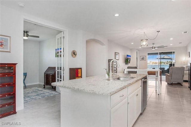 kitchen featuring arched walkways, ceiling fan, a sink, white cabinetry, and open floor plan