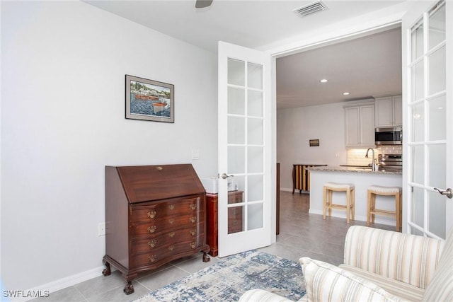 living area with french doors, light tile patterned flooring, visible vents, and baseboards