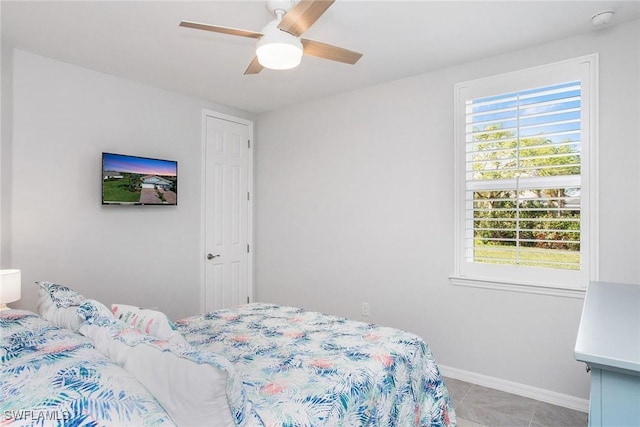 bedroom featuring ceiling fan, light tile patterned floors, and baseboards