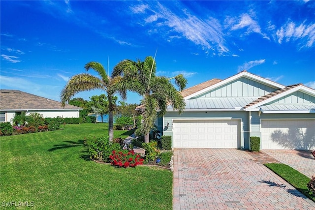 ranch-style house featuring a garage, decorative driveway, board and batten siding, and a front yard