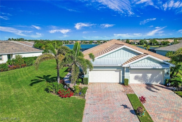 single story home featuring metal roof, a garage, decorative driveway, a standing seam roof, and a front yard