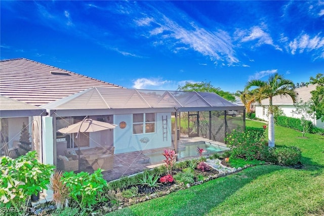 rear view of house featuring glass enclosure, an outdoor pool, a yard, stucco siding, and a patio area