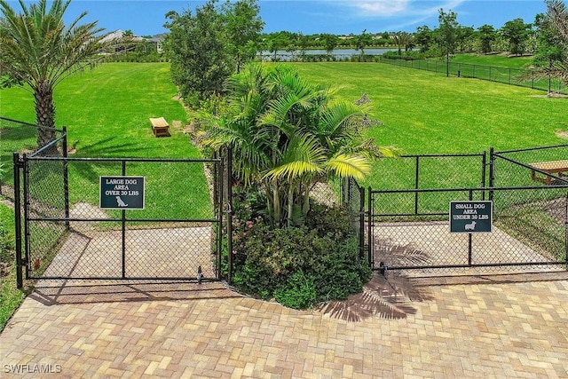 view of gate featuring a water view, fence, and a yard