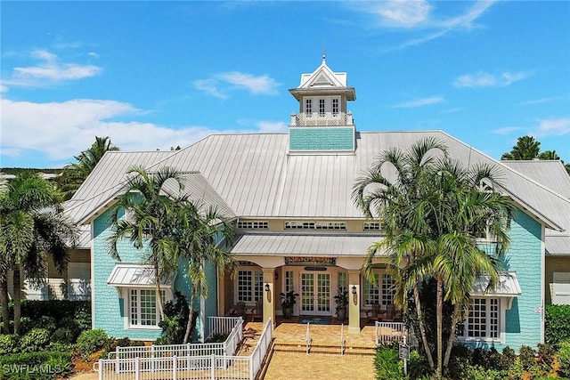 exterior space featuring metal roof, french doors, a standing seam roof, and fence