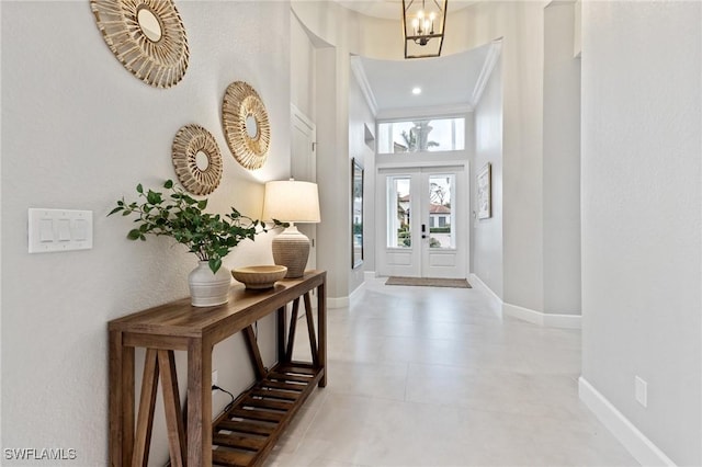 entrance foyer with a notable chandelier, french doors, a high ceiling, and ornamental molding