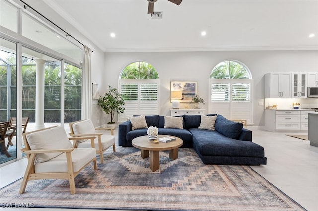 living room featuring a wealth of natural light, crown molding, and ceiling fan