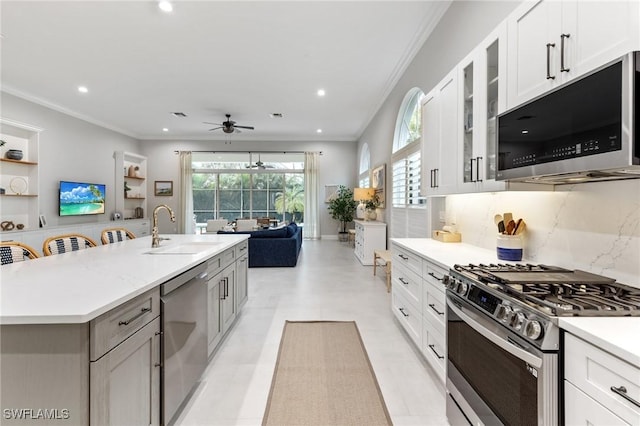 kitchen featuring ceiling fan, sink, stainless steel appliances, an island with sink, and white cabinets