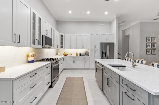 kitchen featuring white cabinets, stainless steel appliances, a center island with sink, and sink