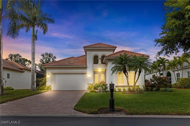 mediterranean / spanish-style home featuring a garage and a yard