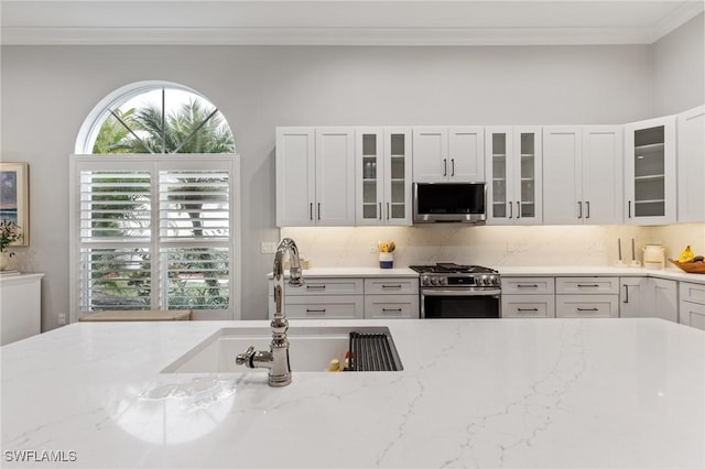 kitchen featuring light stone countertops, stainless steel appliances, white cabinetry, and tasteful backsplash