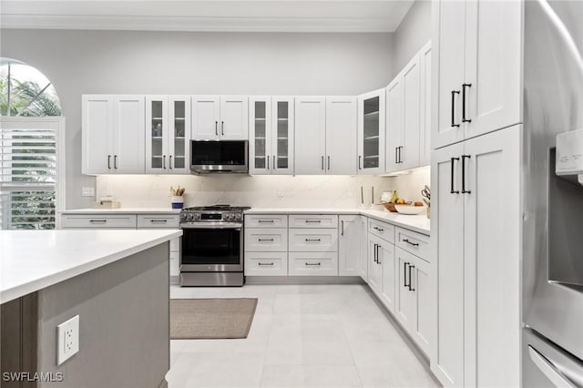 kitchen with decorative backsplash, white cabinetry, light tile patterned floors, and stainless steel appliances