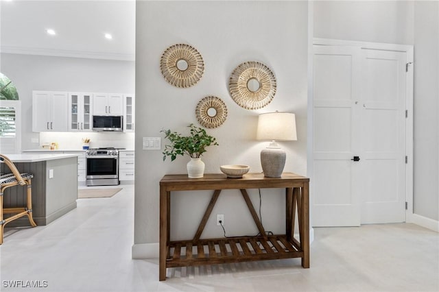 kitchen featuring a kitchen bar, white cabinetry, crown molding, and appliances with stainless steel finishes