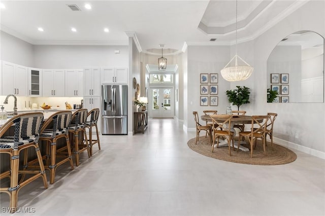 dining room featuring sink, an inviting chandelier, a towering ceiling, and ornamental molding