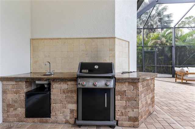 view of patio with an outdoor kitchen, glass enclosure, and a grill