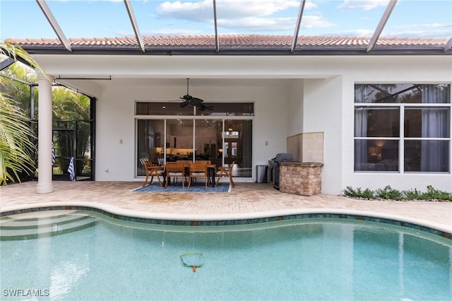 view of swimming pool featuring a patio, glass enclosure, and ceiling fan