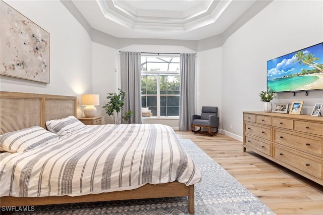 bedroom with a raised ceiling, crown molding, and light hardwood / wood-style flooring