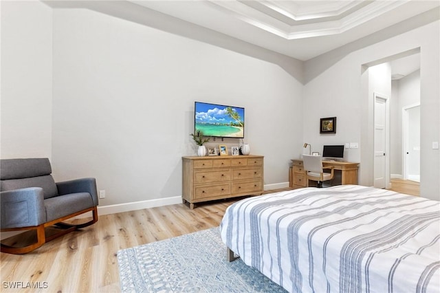 bedroom featuring a tray ceiling, light hardwood / wood-style flooring, and crown molding