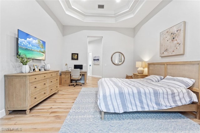 bedroom featuring light hardwood / wood-style flooring, a raised ceiling, and ornamental molding