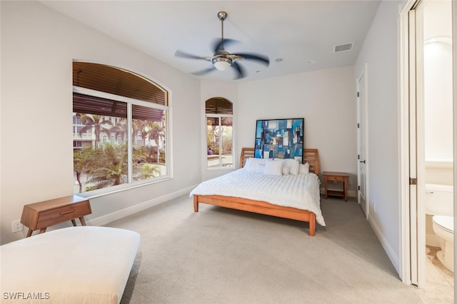 bedroom featuring light carpet, ceiling fan, and ensuite bathroom