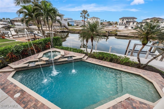 view of swimming pool featuring pool water feature, a water view, an in ground hot tub, and a boat dock