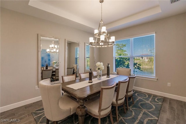 dining room with a notable chandelier and a raised ceiling