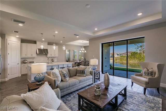 living room with a wealth of natural light, a chandelier, and a tray ceiling