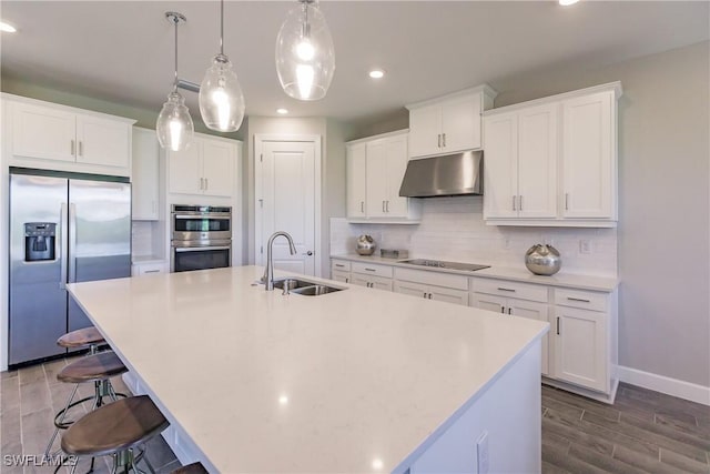 kitchen featuring stainless steel appliances, a center island with sink, white cabinets, and sink