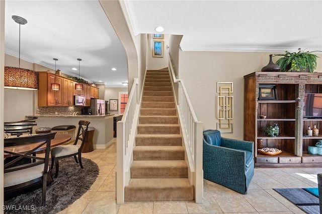 staircase featuring crown molding and tile patterned flooring