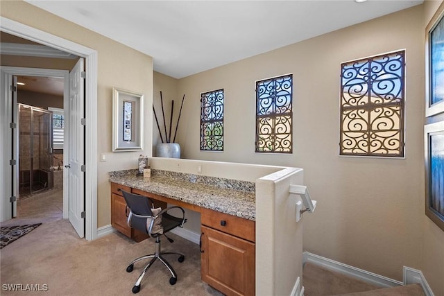 carpeted office space with built in desk and a wealth of natural light