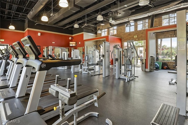 gym featuring brick wall and a high ceiling